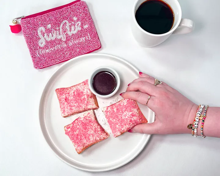 Woman Wearing Friendship Bracelets Holding Beignets Decorated With Pink Sprinkles For A Taylor Swift Event